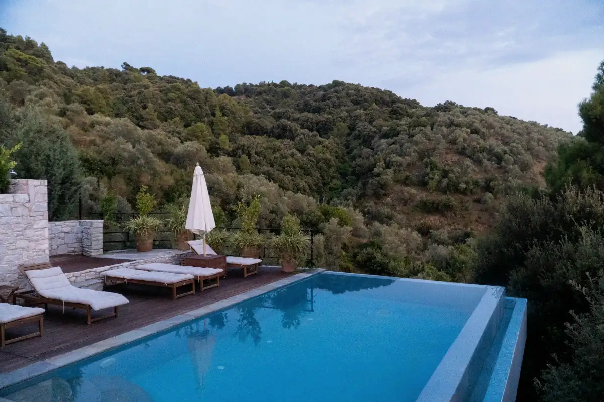 An infinity-edge pool and timber deck on a hillside overlooking wooded hills