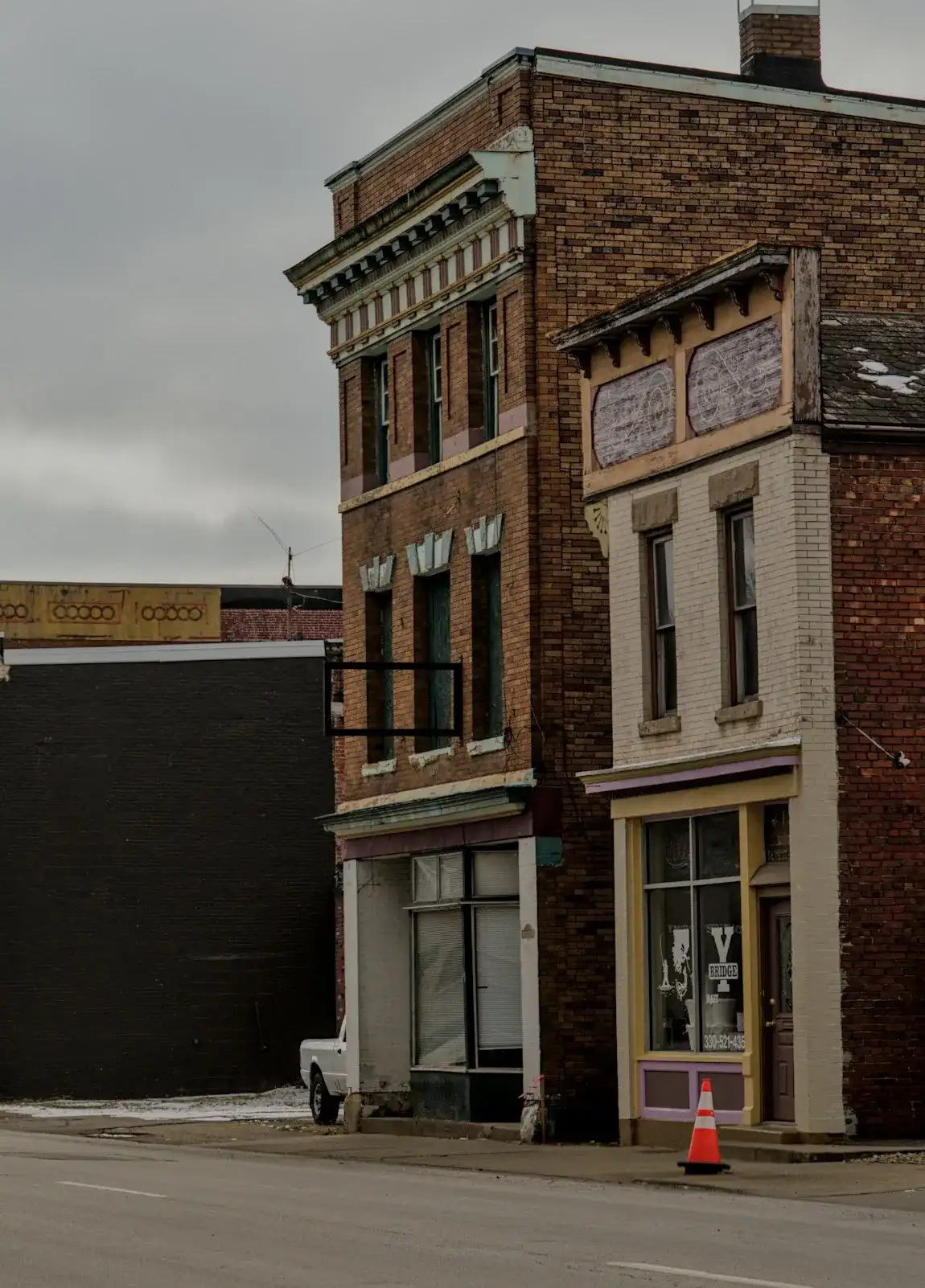 A two-story brick storefront with tall upper windows on a quiet downtown street (stock photo)